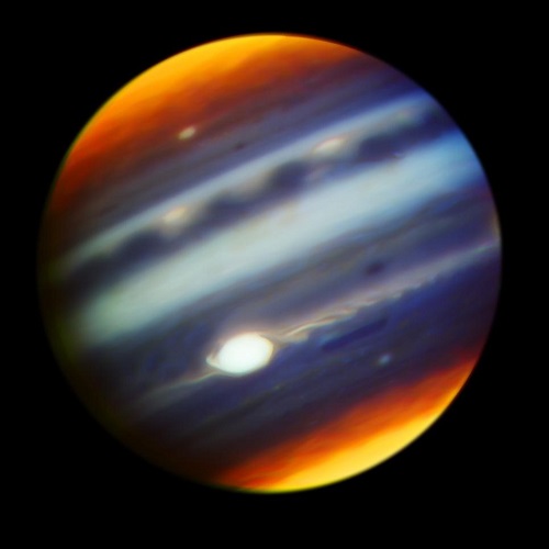 Composite color infrared image of Jupiter, revealing haze particles across altitudes. Great Red Spot (GRS) appears brightest, indicating high-altitude clouds. Yellow/orange features at poles result from auroral-related chemistry.
