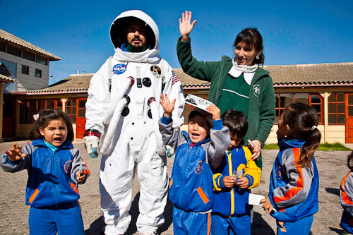 Foto de unos niños junto a un hombre vistiendo un traje de astronauta y una integrante del Observatorio Gemini.