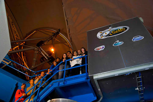 Photo of the Gemini South laser propagation team with the laser shining on the dome overhead and the laser enclosure to the right.