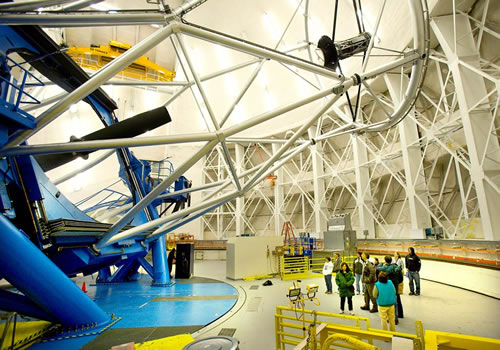 Picture of Gemini North staff family tour participants admire the 8-meter primary mirror with Gemini Director Doug Simons.