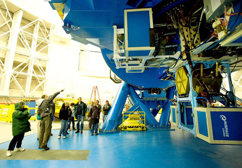 Photo of the Gemini Director Doug Simons pointing to the Gemini North instrument cluster for staff family tour participants.