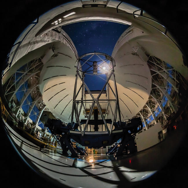 Gemini South telescope inside with a moonlit dome at night.
