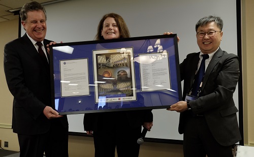 Foto de el Presidente de AURA, Matt Mountain, y la Jefa de la Dirección de Matemáticas y Ciencias Físicas de la NSF, Anne Kinney, entregando una placa conmemorativa al Presidente del KASI, Hyung Mok Lee, durante la ceremonia de firma del KASI en San Francisco.