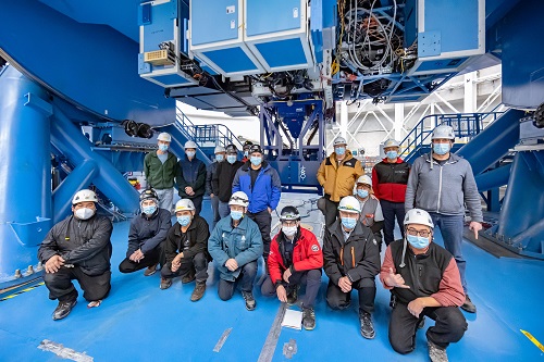 Picture of the NOIRLab staff on the Gemini South floor with the GHOST instrument in the background.