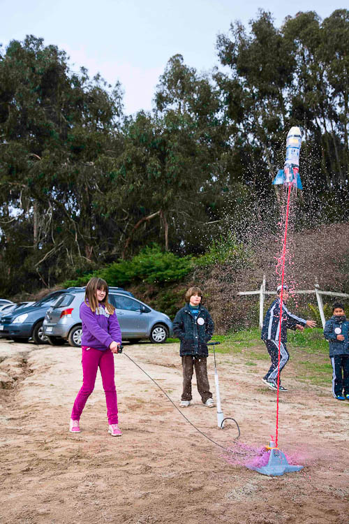 Foto de unos niños lanzando un cohete construido por ellos mismos durante un taller de cohetería.